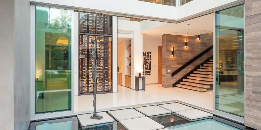 A home’s entrance with sliding glass doors, a metal statue, and a well-lit interior.