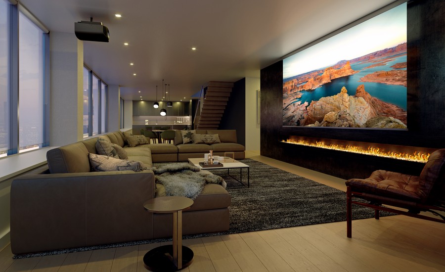 A casual home theater with a Sony projector displaying a landscape image on a large screen above a fire feature.