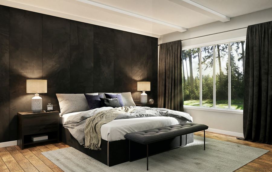 A bedroom softly lit by lamps on nightstands. Open draperies reveal sunlight streaming through the windows.